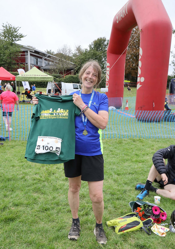 Di at the finish line, holding her medal and clarendon tshirt. 