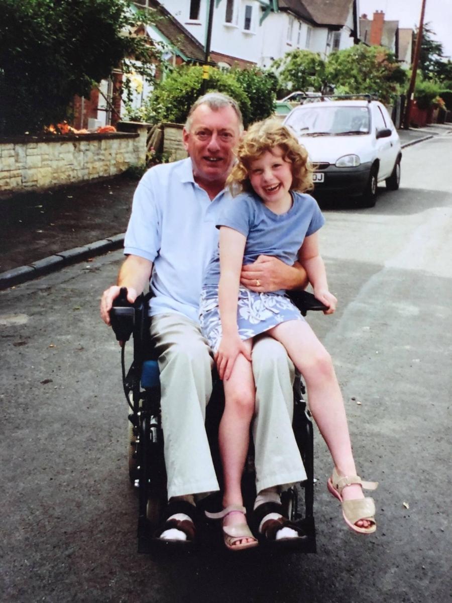 Ellie's grandad in a wheelchair with Ellie on his lap